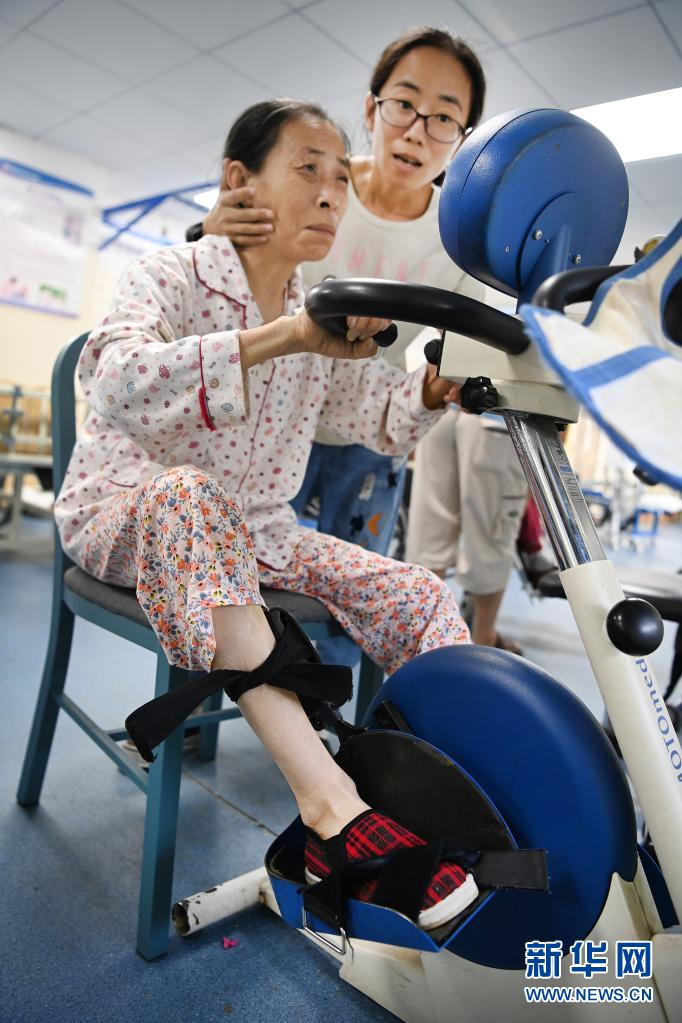 병원 재활훈련실에서 양주메이 씨(오른쪽)가 어머니의 훈련을 돕고 있다. [6월 22일 촬영/사진 출처: 신화망]
