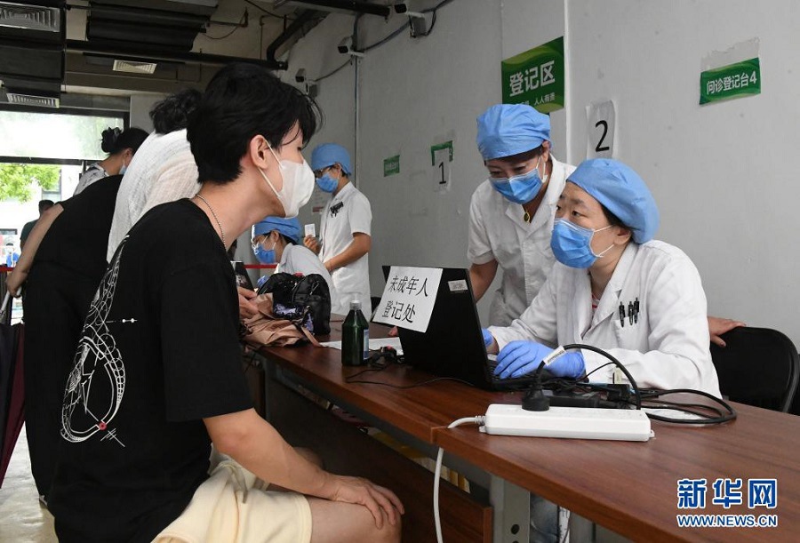 7월 21일, 베이징시 시청구 미성년자 백신 접종소에서 의료진이 한 고등학생의 인적사항을 묻고 있다. [사진 출처: 신화망]