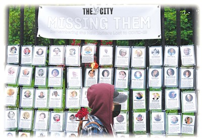 6월 14일, 뉴욕의 한 공동묘지에서 행인이 코로나19 희생자를 추모하기 위해 걸어둔 사진 앞을 걸어가고 있다. [사진 출처: 신화사]