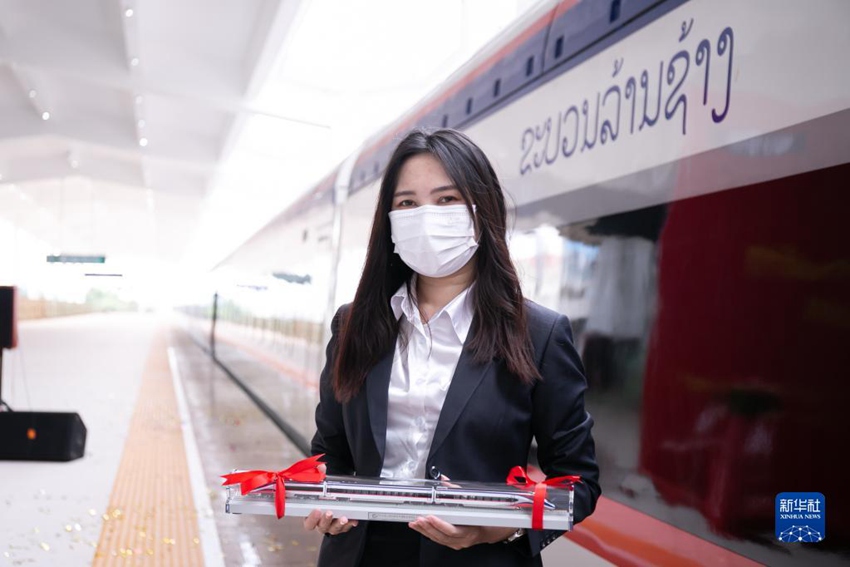 한 여성이 열차 모형을 들고 란창호와 기념사진을 촬영하고 있다. [사진 출처: 신화사]