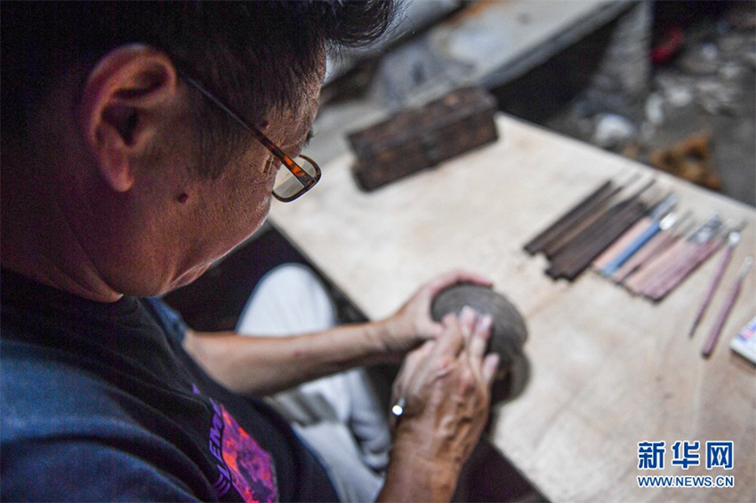 조각 도안을 자세하게 보기 위해 커추펑은 조각작업 과정에서 돋보기를 쓴다. [9월 14일 촬영/사진 출처: 신화사]