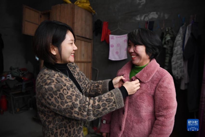11월 17일, 저우원쥐안(왼쪽)이 마을 주민 장둥어에게 예쁜 옷을 입혀주고 있다. [사진 출처: 신화사]