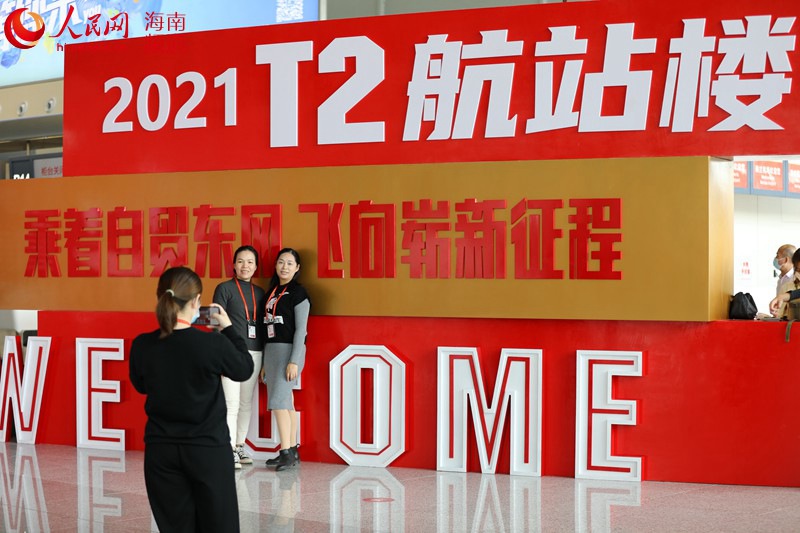 직원들이 T2터미널 광고판 앞에서 기념사진을 찍는다. [사진 출처: 인민망]