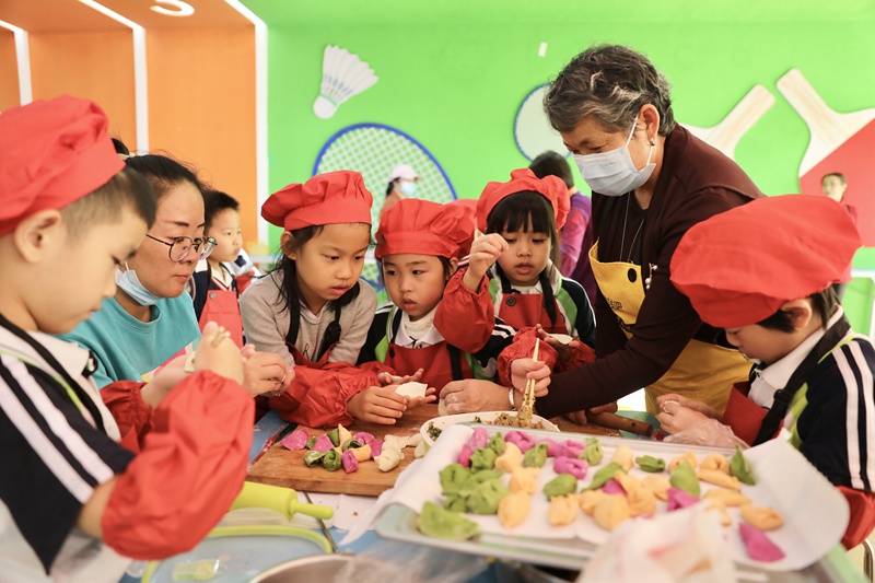 학부모 자원봉사자가 아이들과 함께 간식을 만들고 있다. [사진 출처: 인민망]