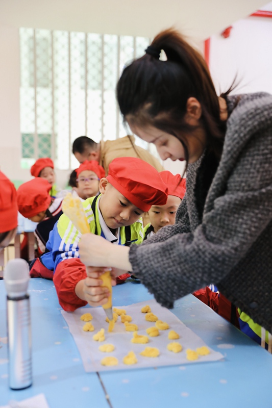 선생님이 아이들과 함께 과자를 만들고 있다. [사진 출처: 인민망]