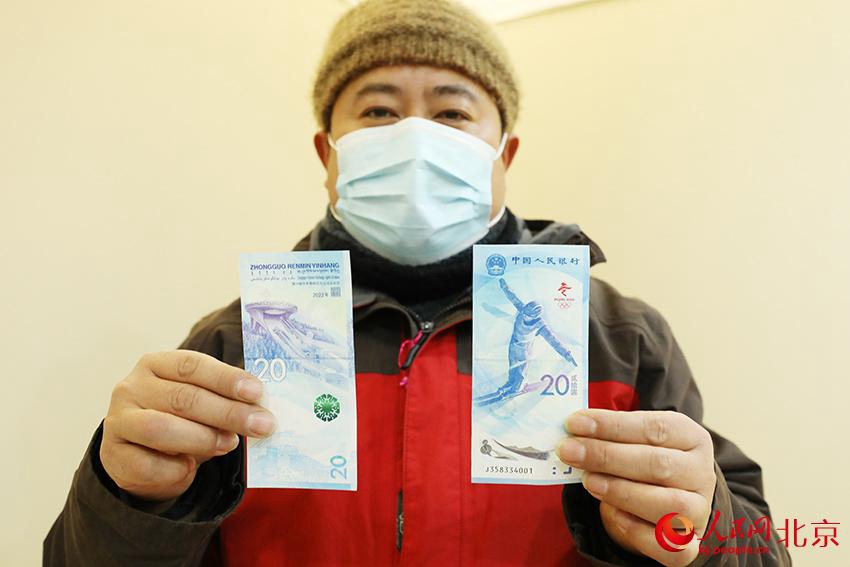 시민 둥모 씨가 방금 산 기념지폐를 보여준다. [사진 출처: 인민망]