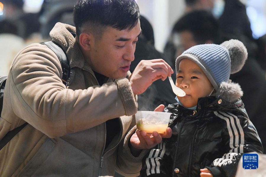 12월 21일 밤 11시 23분, 우루무치 그랜드 바자르 거리, 시민들이 아이들에게 양고기탕을 주었다. [사진 출처: 신화사]