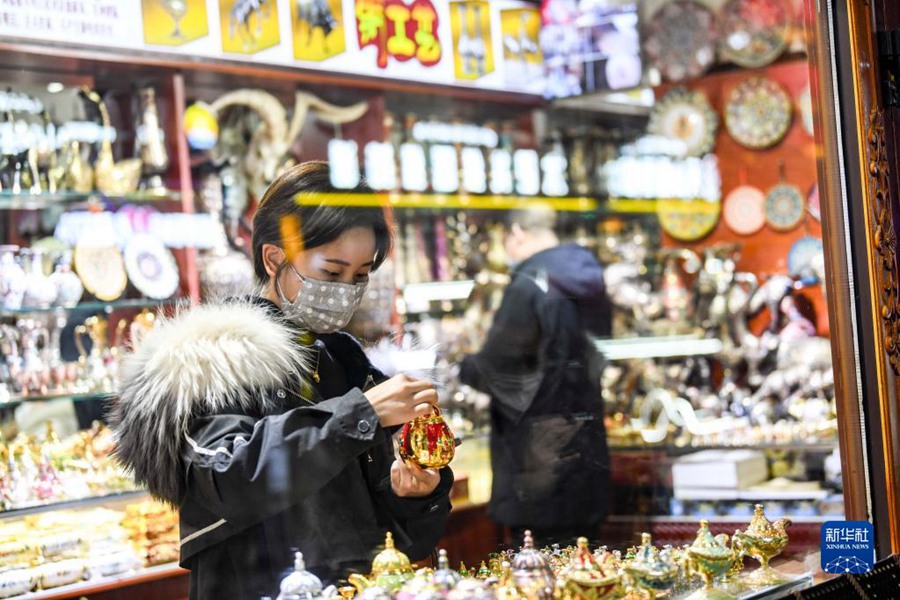 12월 21일 밤 11시 7분, 충칭(重慶)에서 온 관광객 류 씨는 우루무치 그랜드 바자르에서 공예품을 구매한다. 그녀는 당일 우루무치 공항에 내리자마자 저녁에 활기찬 그랜드 바자르 거리를 찾았다. [사진 출처: 신화사]