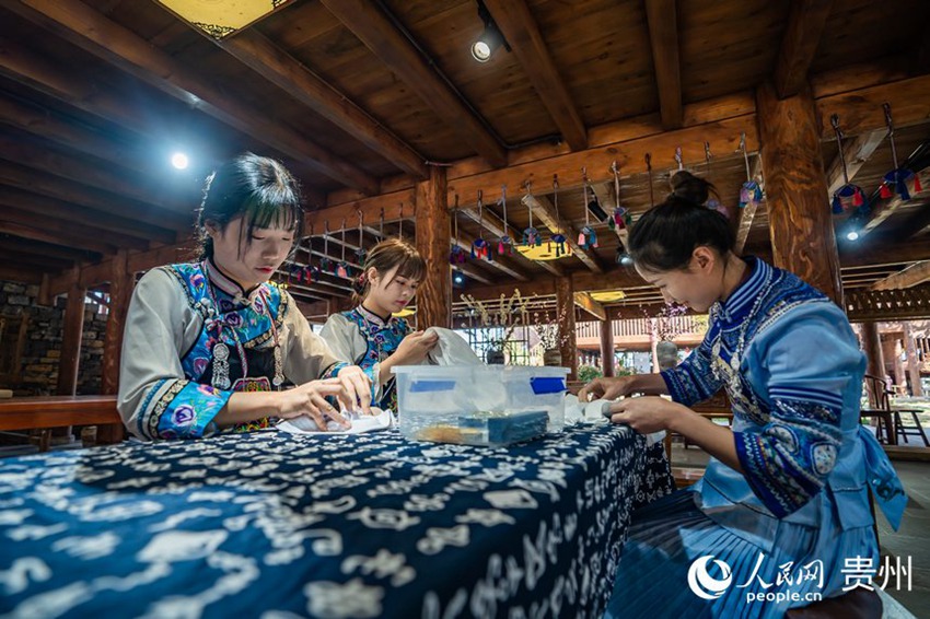 포의족 전통 의상을 입은 여성들이 포의족 특색 염색 공예인 자란 수공예품을 만들고 있다. [사진 출처: 인민망]