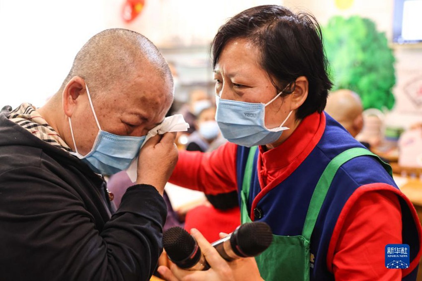 한 노인(왼쪽)이 자원 봉사자의 도움을 회상하며 눈물을 흘리고 있다. [5월 25일 촬영/사진 출처: 신화사]