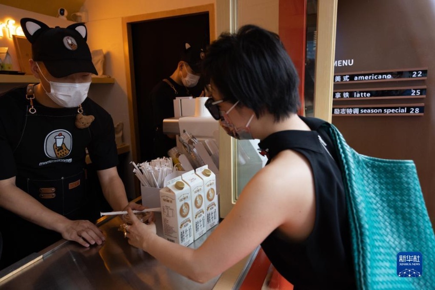 인톈바오(왼쪽)가 고객에게 아이스 아메리카노를 건네고 있다. [7월 16일 촬영/사진 출처: 신화사]