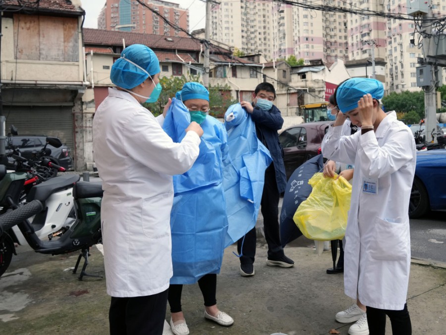 접종팀 의료진들이 단지 앞에서 마스크를 착용하고 방역복을 입고 있다. [12월 5일 촬영/사진 출처: 신화사]