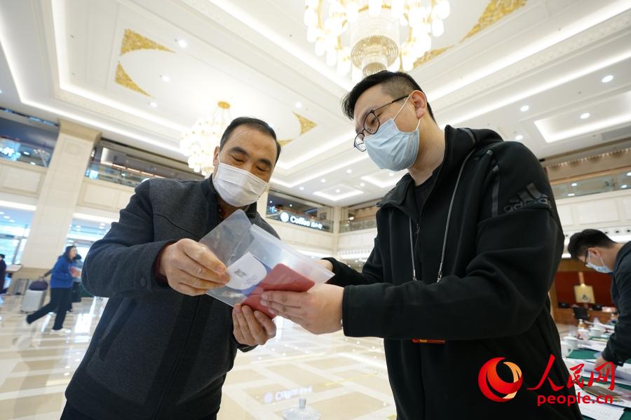 3월 2일, 베이징회의센터 숙소에서 전국정협 위원이 접수를 위해 현장 관계자의 안내에 따라 사인하고, 아이디카드와 회의자료를 수령한다. [사진 출처: 인민망]