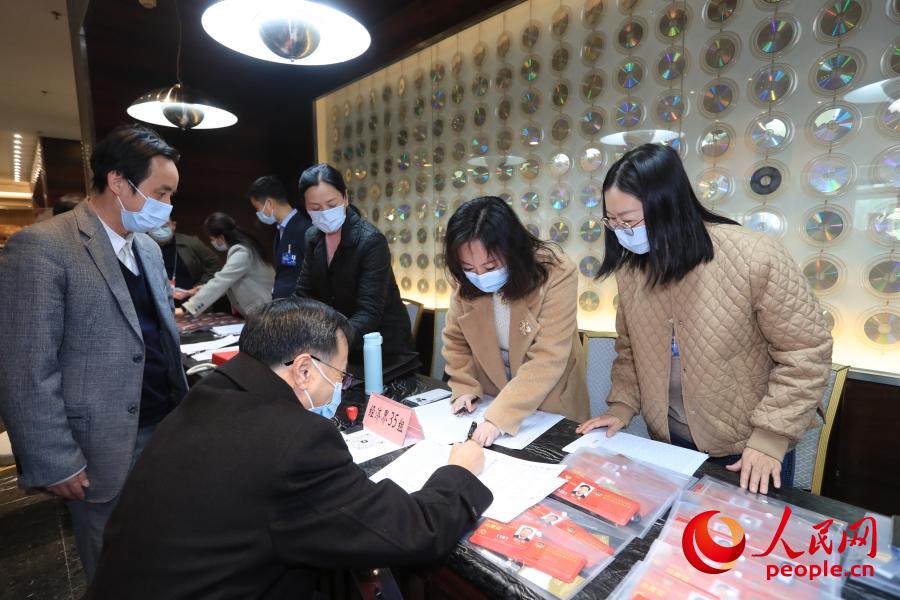 3월 2일, 베이징철도빌딩 숙소에서 전국정협 위원들이 접수를 위해 현장 관계자들의 안내에 따라 사인하고, 아이디카드와 회의자료를 수령한다. [사진 출처: 인민망]