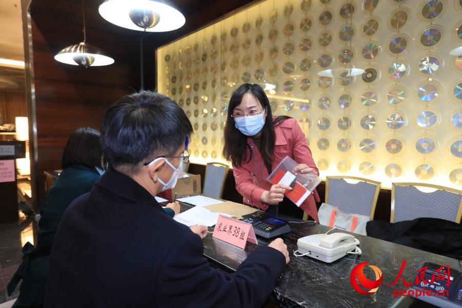 3월 2일, 베이징철도빌딩 숙소에서 전국정협 위원들이 접수를 위해 현장 관계자의 안내에 따라 사인하고, 아이디카드와 회의자료를 수령한다. [사진 출처: 인민망]