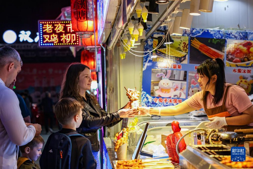 러시아 여행객이 지린성 훈춘시 한탕(漢唐)거리 야시장에서 음식을 구매하고 있다. [사진 출처: 신화사]