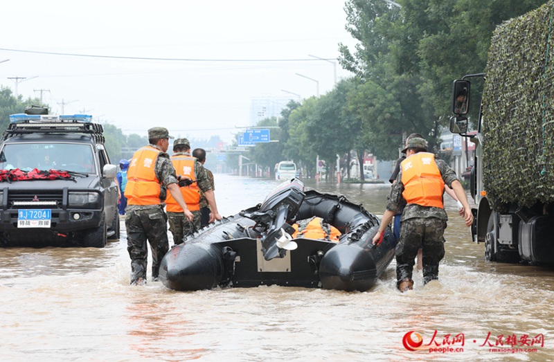 8월 2일 오전 줘저우시 107번 국도 피해 구간에 수십 명의 무장경찰 모 부대 장병들이 도착해 이재민들에게 음식과 식수를 보낼 준비를 했다. 사진은 무장경찰 장병들이 고무보트를 운반하는 모습. [사진 출처: 인민망]