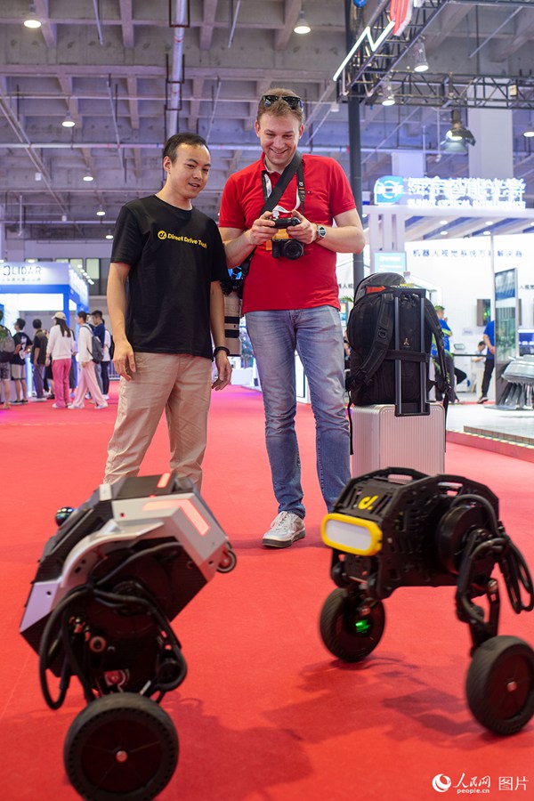 8월 16일, 참가업체 직원이 관람객에게 바퀴 달린 로봇 조작법을 알려주고 있다. [사진 출처: 인민망]