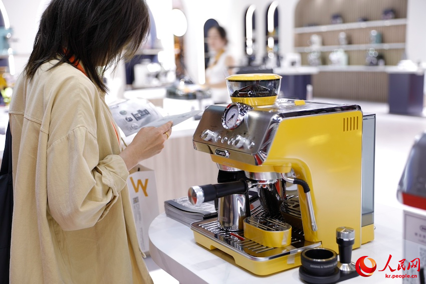관람객이 소비품 전시장에서 커피머신 기능을 살펴본다. [11월 5일 촬영/사진 출처: 인민망]