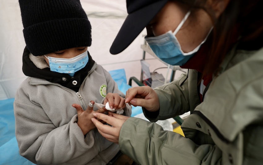 12월 21일 지스산현 다허자진의 임시 대피소, 의사가 어린이의 상처를 치료한다.