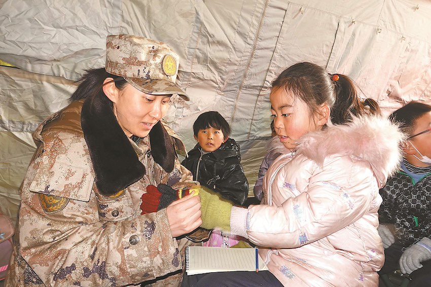 간쑤성 지스산현 스위안진 샤오훙핑(肖紅坪)촌 대피소, 아이들이 육군 제76집단군이 전달하는 장갑을 받고 있다. [12월 23일 촬영/사진 출처: 신화사]