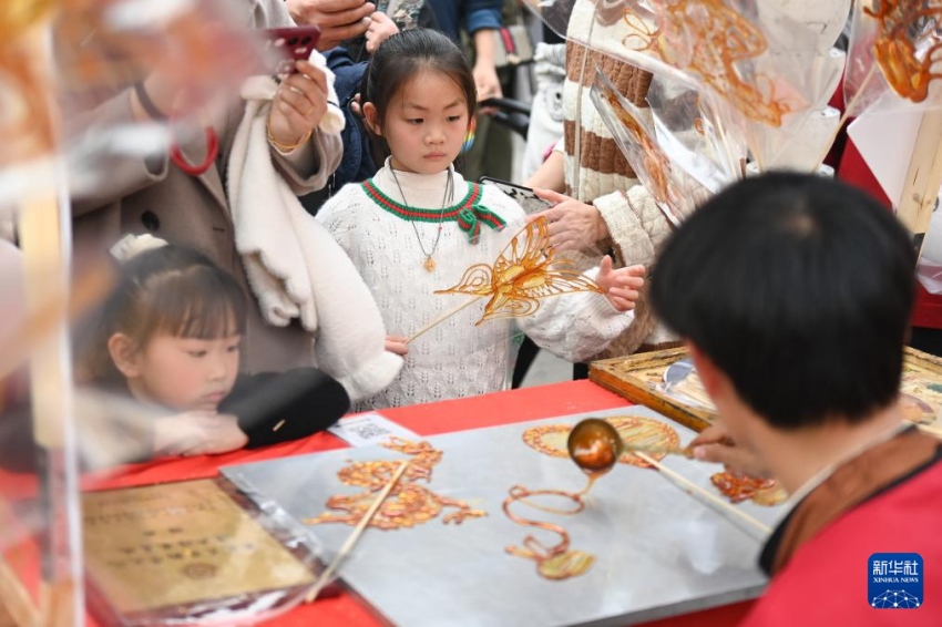 14일 관광객들이 저장성 닝보시 펑화구 시커우진 싼리창제거리 시장에서 탕화(糖畫) 제작을 구경하고 있다. 