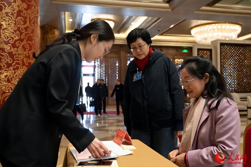 베이징 컨벤션센터에서 제14기 전인대 제2차 회의에 참석하는 베이징 대표단이 직원의 안내에 따라 출입증 및 회의 자료를 수령하고 있다. [3월 3일 촬영/사진 출처: 인민망]