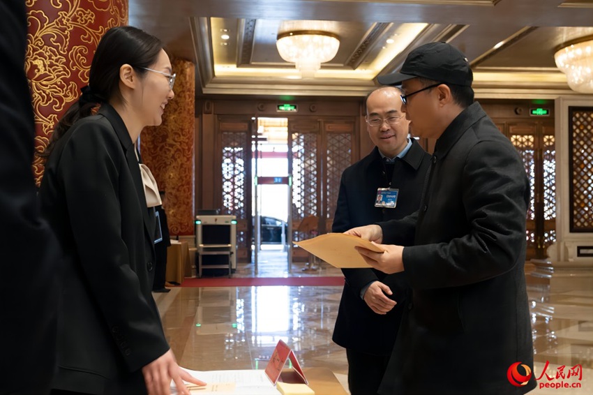 베이징 컨벤션센터에서 제14기 전인대 제2차 회의에 참석하는 베이징 대표단이 직원의 안내에 따라 출입증 및 회의 자료를 수령하고 있다. [3월 3일 촬영/사진 출처: 인민망]