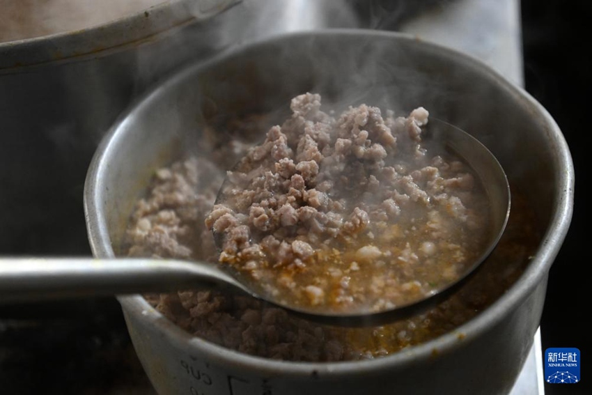 류융 씨가 쌀국수에 다진 고기를 넣고 있다. [1월 25일 촬영/사진 출처: 신화사]