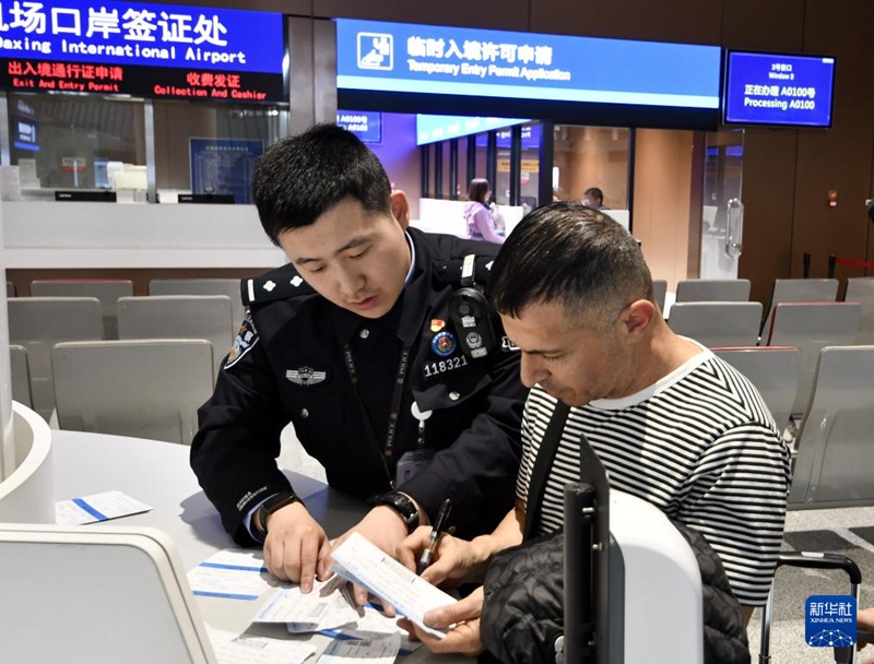 외국인 관광객이 베이징 다싱공항 입국 심사대 경찰의 안내로 입국 카드를 작성한다. [12월 27일 촬영/사진 출처: 신화사]