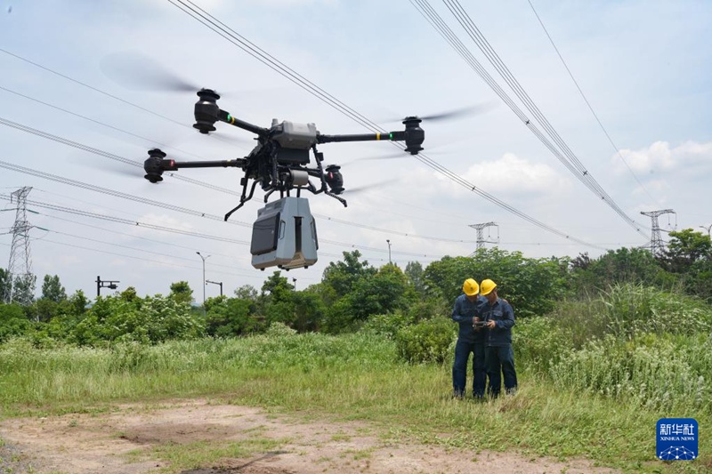 주지(諸暨)시 500kV 송전선로 현장에서 작업자가 다장(大疆·DJI) 드론에 탑재한 접지선 단선 전기 수리 로봇을 조종해 선로를 수리하고 있다. [5월 22일 촬영/사진 출처: 신화사]