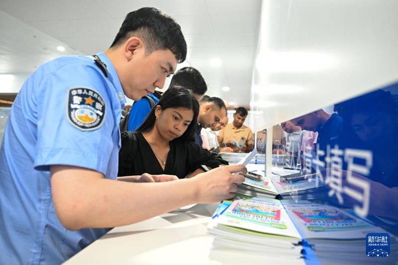 톈진 빈하이 국제공항 T1 터미널에서 톈진공항 출입국 경찰이 인도네시아에서 온 관광객의 외국인 입국 카드 작성을 돕고 있다. [8월 27일 촬영/사진 출처: 신화사]