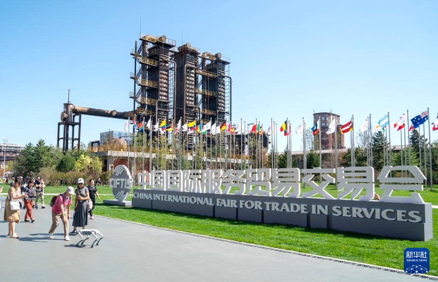 사람들이 교역회 로고 앞에서 로봇개와 인사한다. [9월 14일 촬영/사진 출처: 신화사]