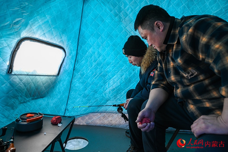 텐트 안에서 얼음낚시꾼이 고기가 잡히기를 기다리고 있다.