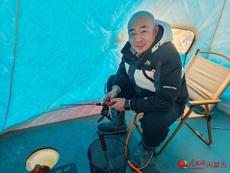 텐트 안에서 얼음낚시꾼이 고기가 잡히기를 기다리고 있다.