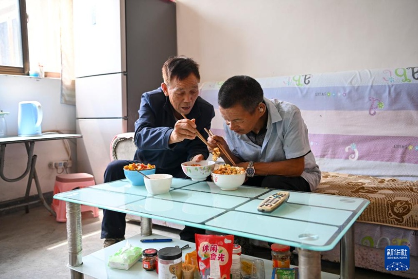 마을 주민이 친하이쑹에게 반찬을 집어주고 있다. [2025년 8월 27일 촬영/사진 출처: 신화사]