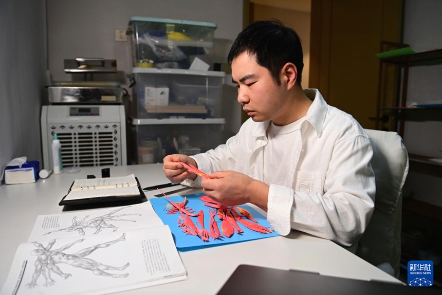 장보 씨가 작업실에서 책을 참고하며 공예 부품의 크기를 조정한다. [1월 13일 촬영/사진 출처: 신화사]