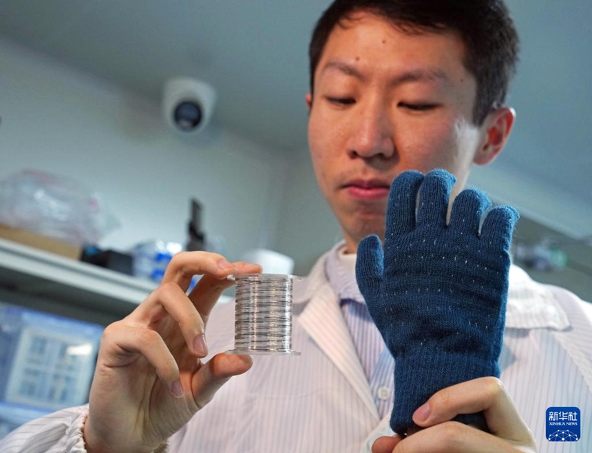 연구원이 롤 형태의 ‘섬유 칩’과 이를 직조해 제작한 스마트 촉각 장갑을 선보이고 있다. [1월 19일 촬영/사진 출처: 신화사]