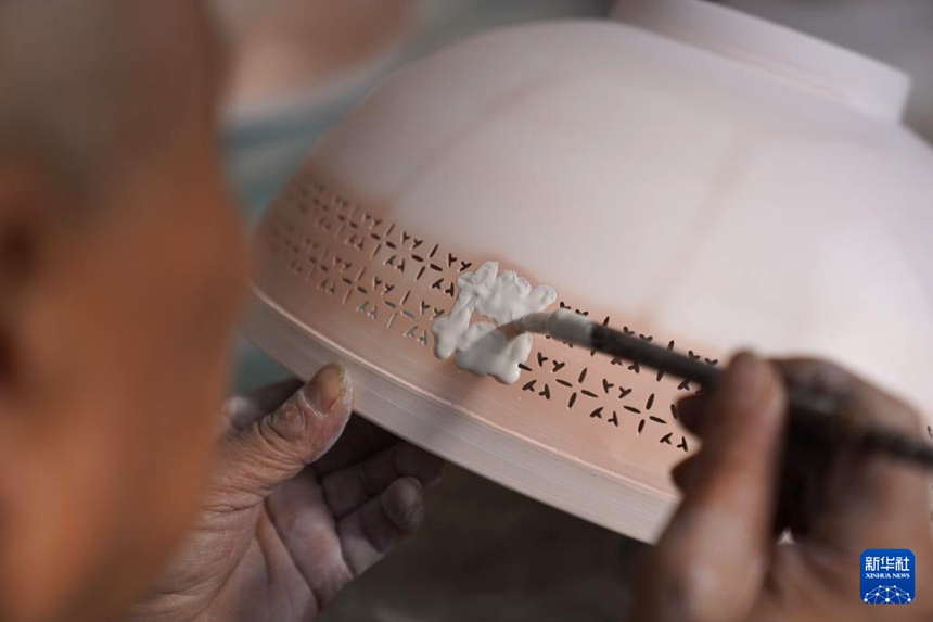 루젠더 씨가 박태자기 그릇에 유약을 채우고 있다. [3월 10일 촬영/사진 출처: 신화사]