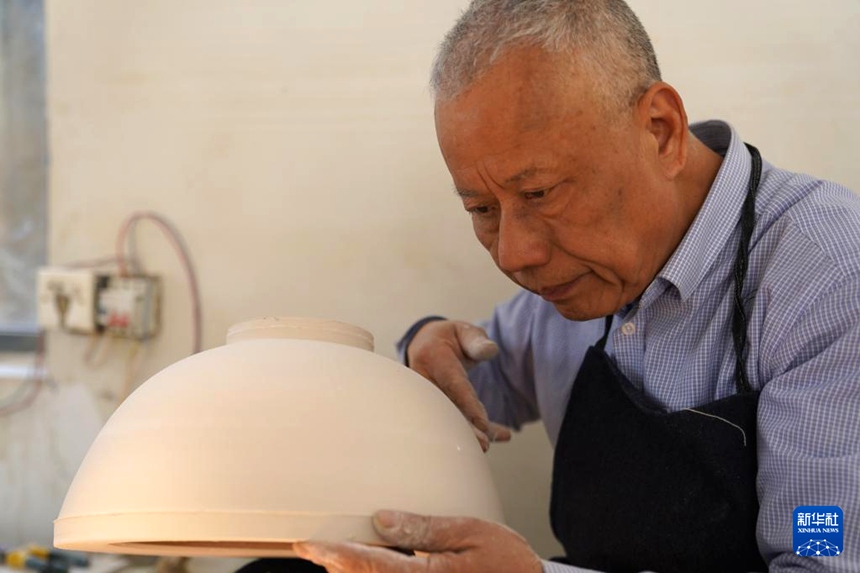 루젠더 씨가 박태자기 기물을 가볍게 두드려 두께가 기준에 도달했는지 확인하고 있다. [3월 10일 촬영/사진 출처: 신화사]