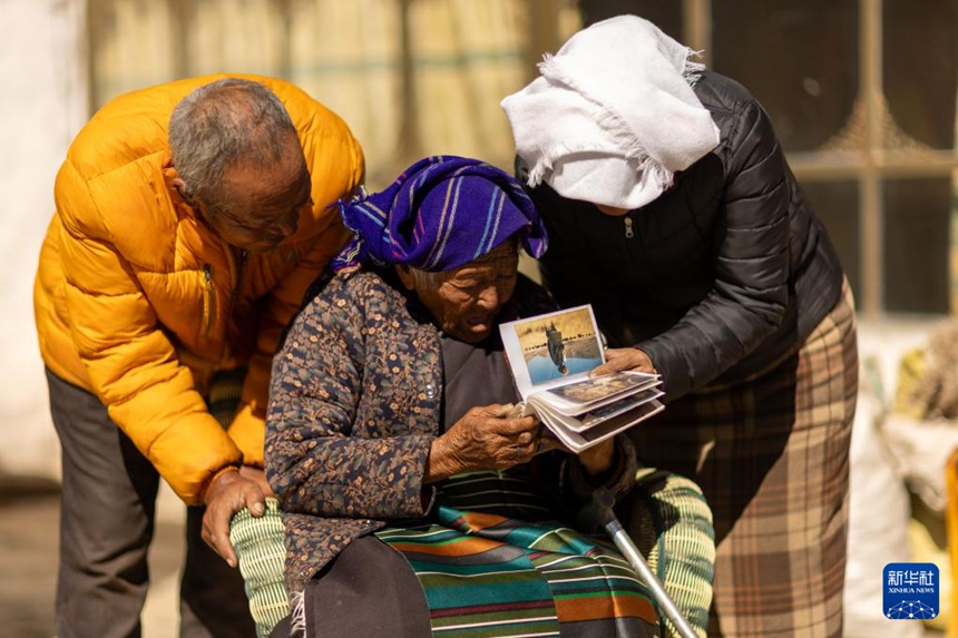 95세 언니 궁줴취전이 집에서 큰아들 및 며느리와 함께 앨범을 펴 보고 있다. [3월 6일 촬영/사진 출처: 신화사]