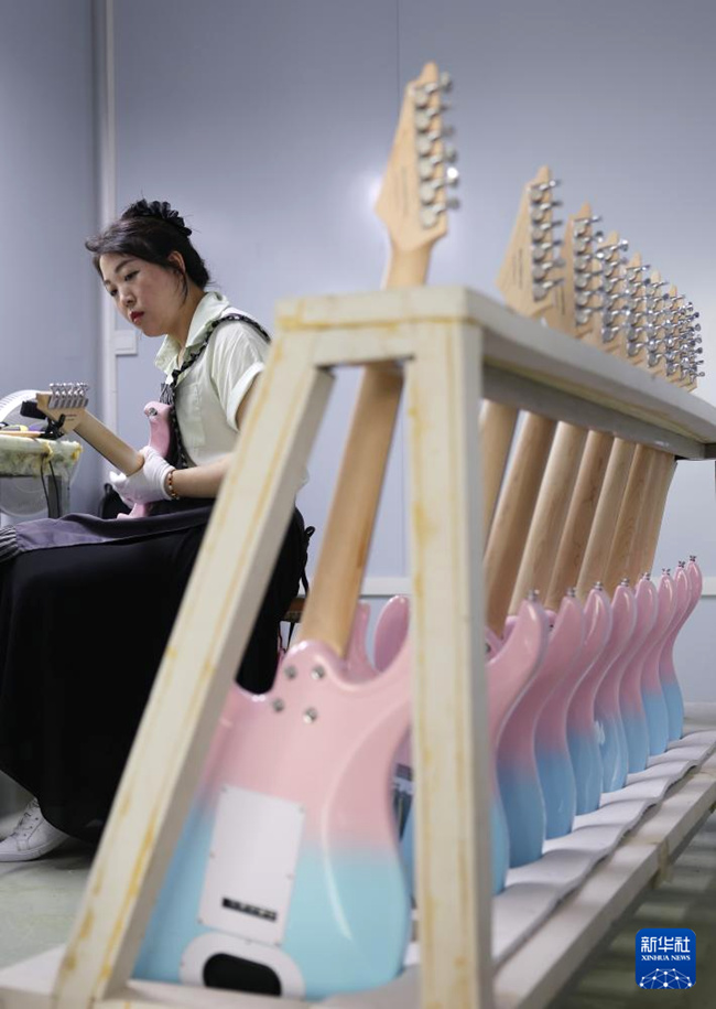 둥안현 기타 산업단지에서 직원이 일렉트릭 기타의 음정을 조절하고 있다. [5월 12일 촬영/사진 출처: 신화사]