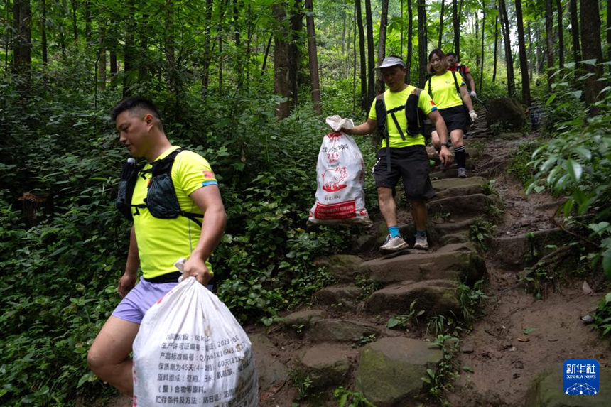 자원봉사자들이 주운 쓰레기를 가지고 산에서 내려오고 있다. [5월 24일 촬영/사진 출처: 신화사]