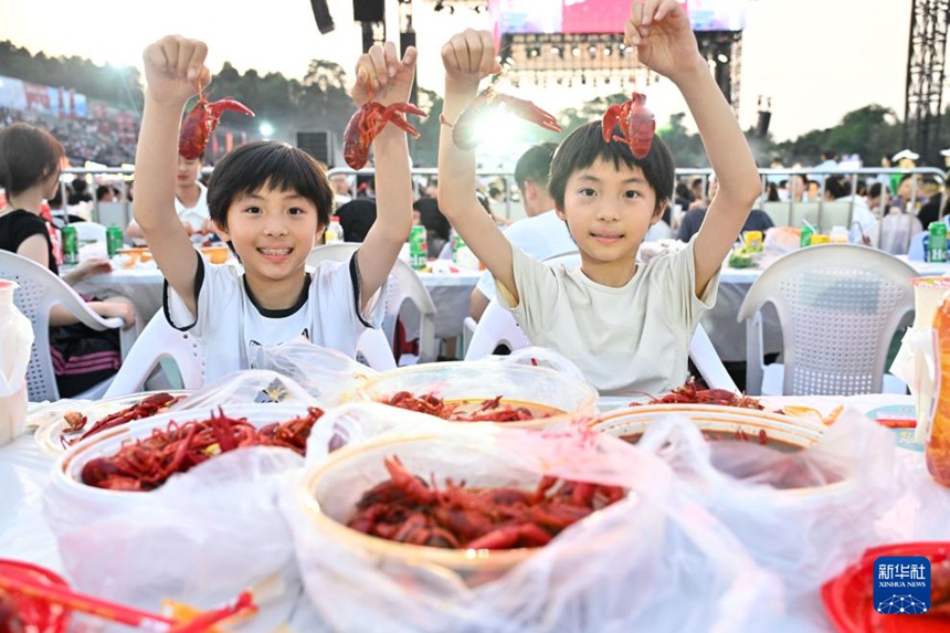 쉬이 샤오룽샤 축제 광장에서 쌍둥이 남자아이가 샤오룽샤를 들어 올려  보여주고 있다. [6월 12일 촬영/사진 출처: 신화사]