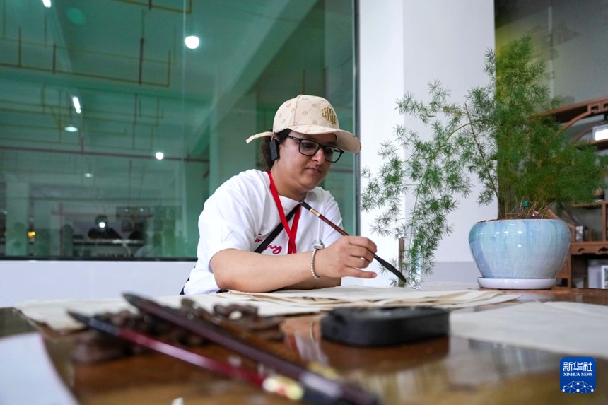 멍하이현의 한 차 기업에서 외국인 관광객이 차병(茶餅: 찻잎을 벽돌 모양이나 원반형으로 뭉쳐 굳힌 것) 종이 쓰기 체험을 하고 있다. [7월 15일 촬영/사진 출처: 신화사]