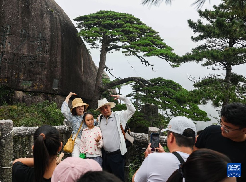 지난 18일, 관광객들이 황산풍경구 영객송(迎客松) 앞에서 기념사진을 찍고 있다. [사진 출처: 신화사]