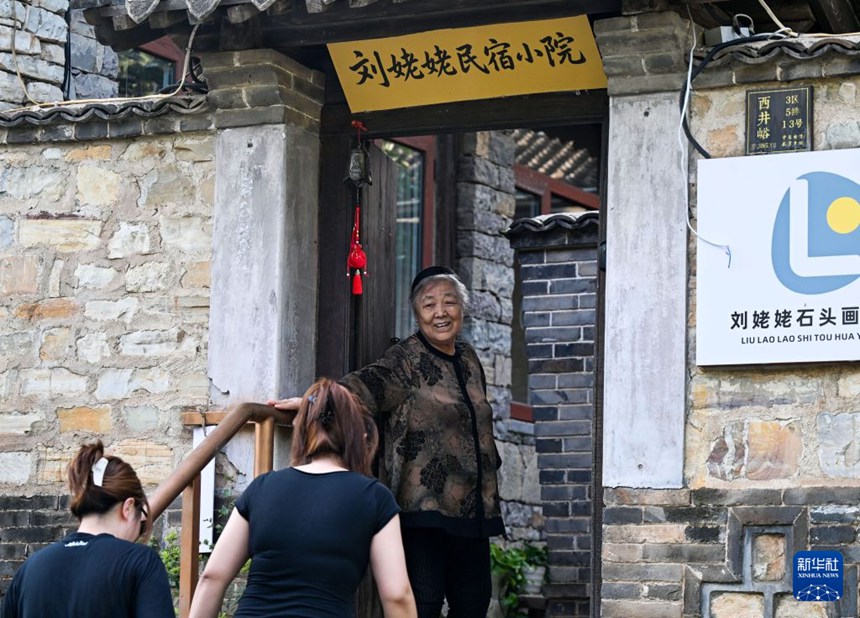 류안친 씨는 ‘류할머니 민박집’ 문 앞에서 손님들을 환영한다. [8월 4일 촬영/사진 출처: 신화사]