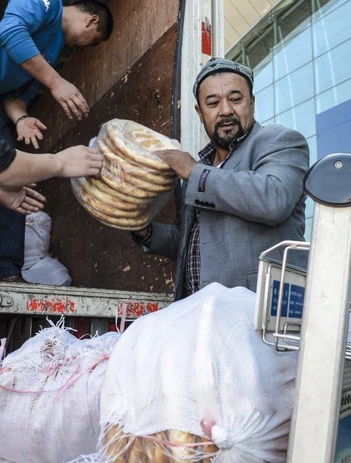 4월 22일, 우루무치(烏魯木齊) 공항에서 아리무(阿里木, 우측) 씨와 애심(愛心)기업 직원들이 함께 포장한 낭(饢, 위구르족이 먹는 구운 빵의 일종)을 운반하고 있다.