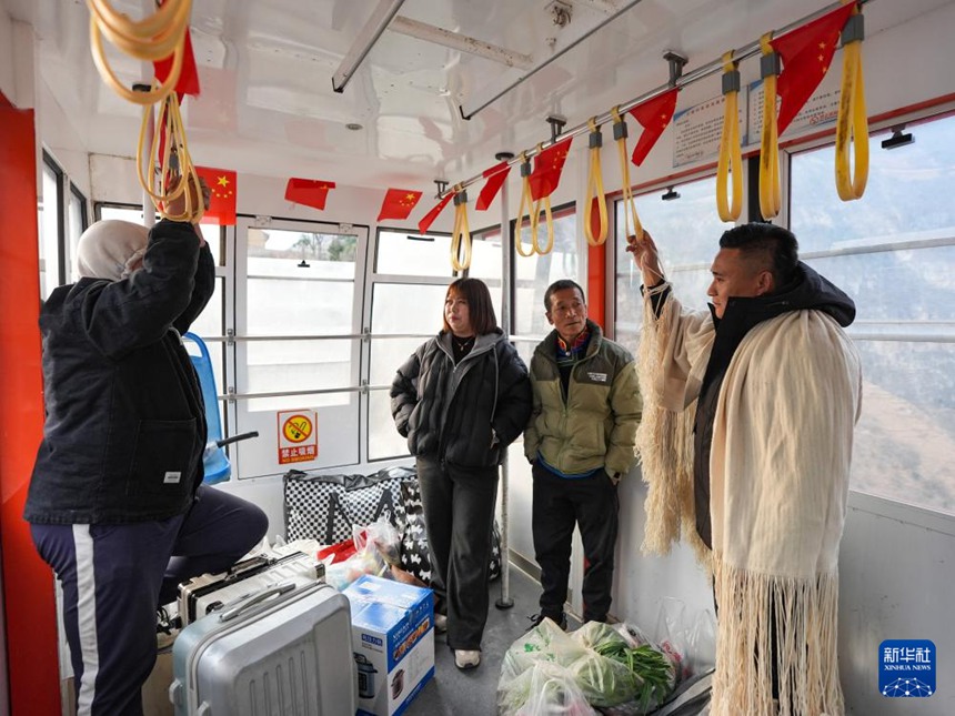 정왕춘 대표가 구루촌 케이블카 안에서 외지에서 일을 마치고 돌아오는 주민과 이야기한다. [1월 28일 촬영/사진 출처: 신화사]